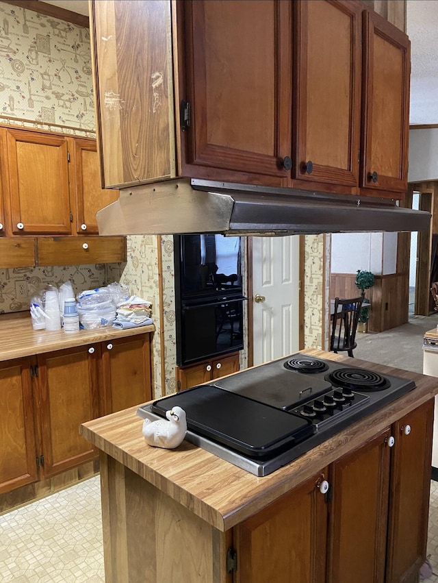 kitchen with butcher block countertops, black electric stovetop, brown cabinets, and exhaust hood