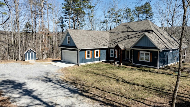 view of front of home with a storage shed, board and batten siding, a front yard, a garage, and driveway