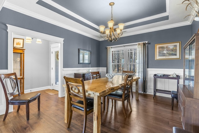 dining room featuring a tray ceiling, wood finished floors, wainscoting, and an inviting chandelier