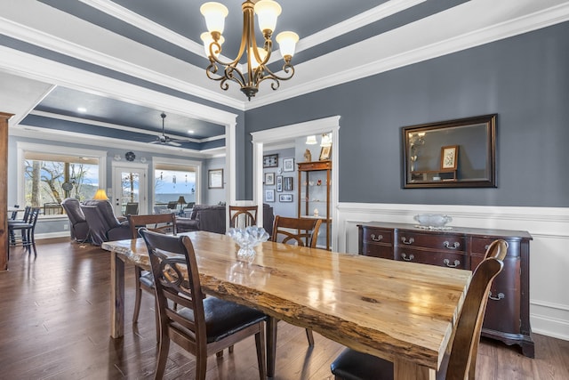 dining space with ornamental molding, a tray ceiling, ceiling fan with notable chandelier, and wood finished floors