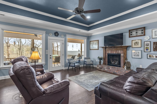 living area featuring baseboards, a tray ceiling, hardwood / wood-style flooring, and crown molding