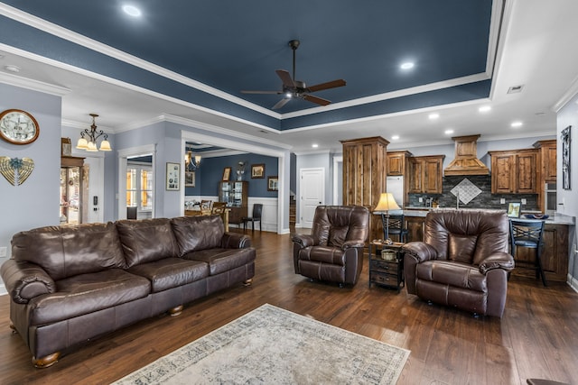 living area with dark wood-type flooring, a tray ceiling, recessed lighting, and ceiling fan with notable chandelier