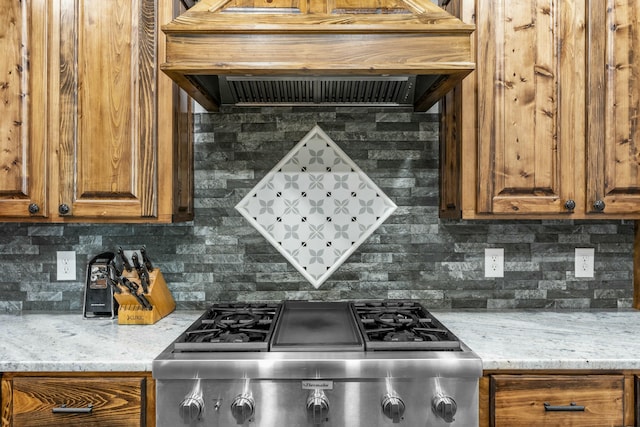 kitchen with decorative backsplash, brown cabinets, range, and custom exhaust hood