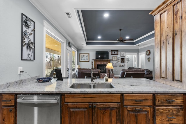 kitchen featuring ceiling fan, a tray ceiling, crown molding, a fireplace, and stainless steel dishwasher