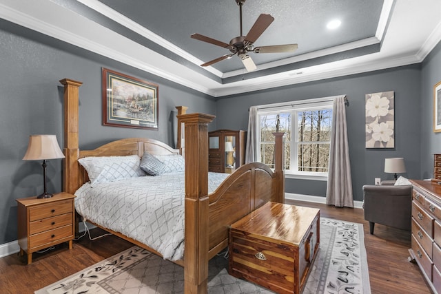 bedroom featuring a raised ceiling, crown molding, baseboards, and wood finished floors