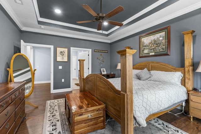 bedroom with wood finished floors, ornamental molding, a raised ceiling, and baseboards