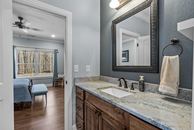 bathroom with ornamental molding, ceiling fan, vanity, wood finished floors, and baseboards