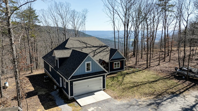 view of front of house featuring a garage, driveway, and a shingled roof