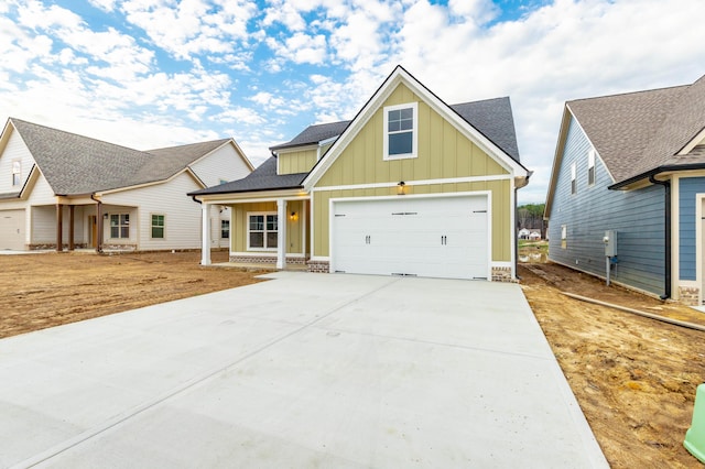 craftsman inspired home featuring a shingled roof, a porch, board and batten siding, and concrete driveway