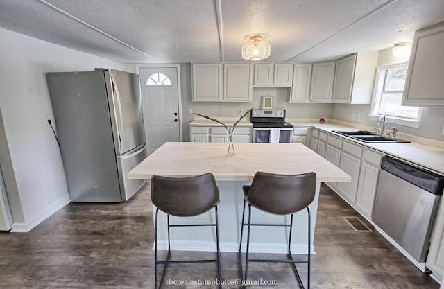 kitchen featuring a center island, sink, a textured ceiling, appliances with stainless steel finishes, and dark hardwood / wood-style floors
