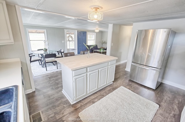 kitchen featuring white cabinetry, a kitchen island, stainless steel refrigerator, and dark hardwood / wood-style floors