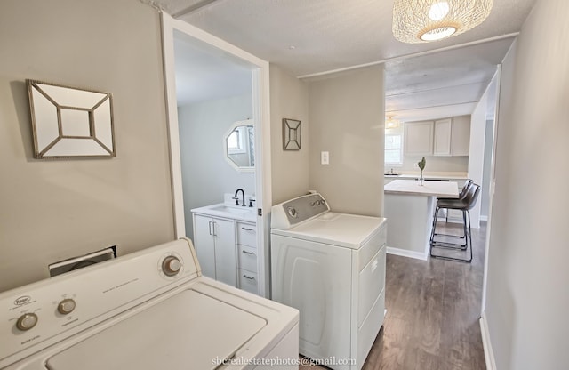 laundry room with independent washer and dryer, sink, and dark wood-type flooring