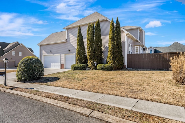 view of front of home with an attached garage, fence, a front lawn, and concrete driveway