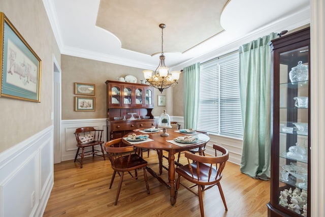 dining area with a chandelier, wainscoting, ornamental molding, and light wood-type flooring