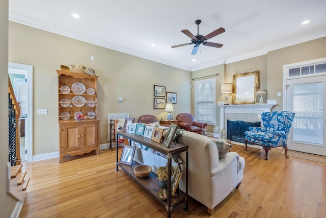 living area with ornamental molding, light wood-type flooring, and a tile fireplace