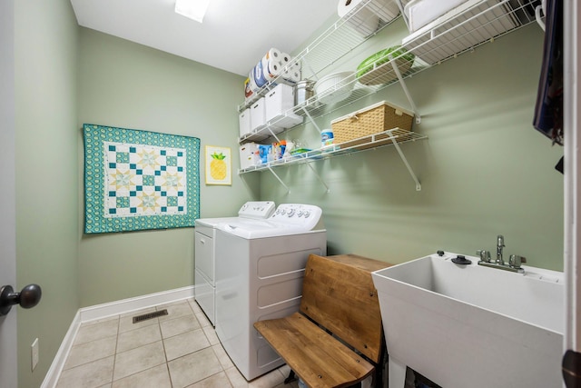 clothes washing area featuring washing machine and clothes dryer, light tile patterned floors, visible vents, a sink, and laundry area