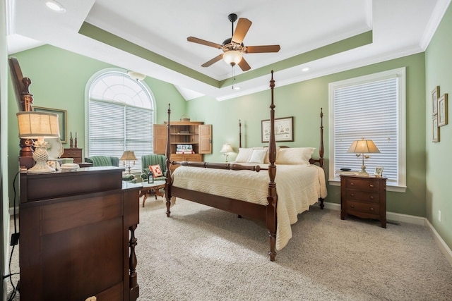 carpeted bedroom featuring ceiling fan, ornamental molding, a raised ceiling, and baseboards