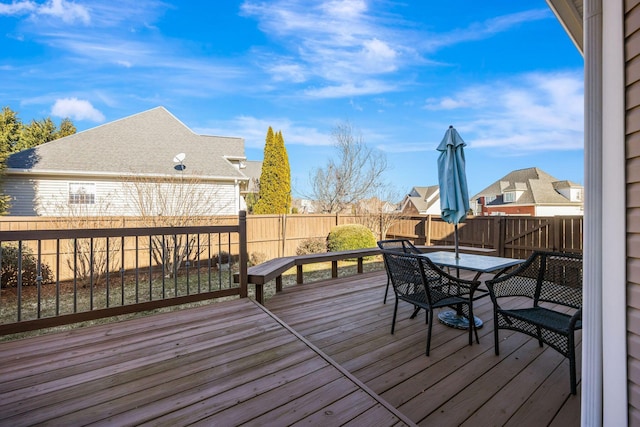 wooden deck featuring outdoor dining space, a fenced backyard, and a residential view