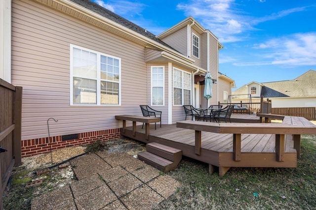 rear view of house featuring crawl space, a deck, and outdoor dining area