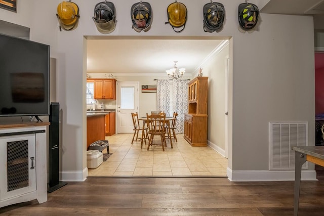 dining area with light hardwood / wood-style floors, crown molding, and a notable chandelier