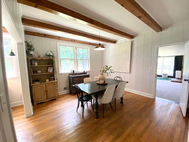 dining space featuring beam ceiling, wood-type flooring, and a wealth of natural light