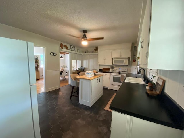 kitchen with a kitchen island, butcher block countertops, sink, white cabinets, and white appliances