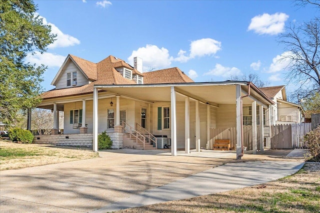 view of front of house featuring fence, roof with shingles, covered porch, a chimney, and driveway