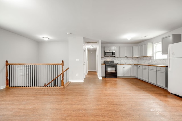 kitchen with sink, decorative backsplash, white refrigerator, electric range, and light hardwood / wood-style flooring