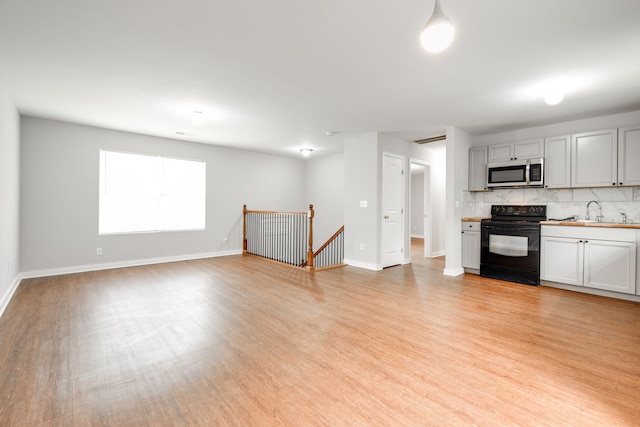 kitchen featuring tasteful backsplash, sink, light hardwood / wood-style flooring, and electric range