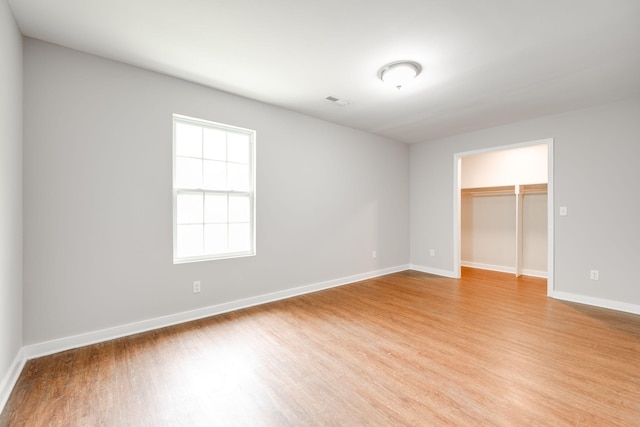 unfurnished bedroom featuring a spacious closet, light wood-type flooring, and a closet