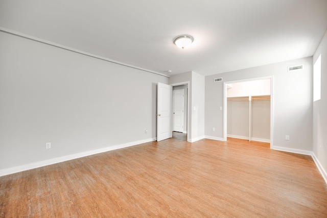 unfurnished bedroom with a walk in closet and light hardwood / wood-style floors