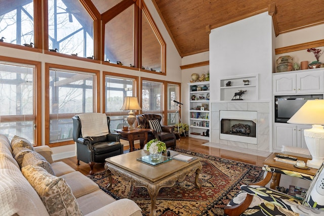 living room with a tile fireplace, built in features, high vaulted ceiling, wood ceiling, and light wood-type flooring