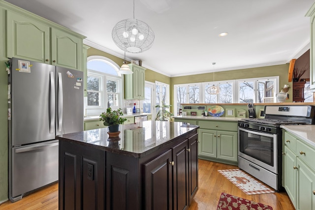 kitchen with stainless steel appliances, ornamental molding, hanging light fixtures, and light hardwood / wood-style flooring