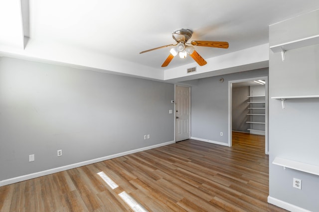 unfurnished room featuring a ceiling fan, baseboards, visible vents, and wood finished floors