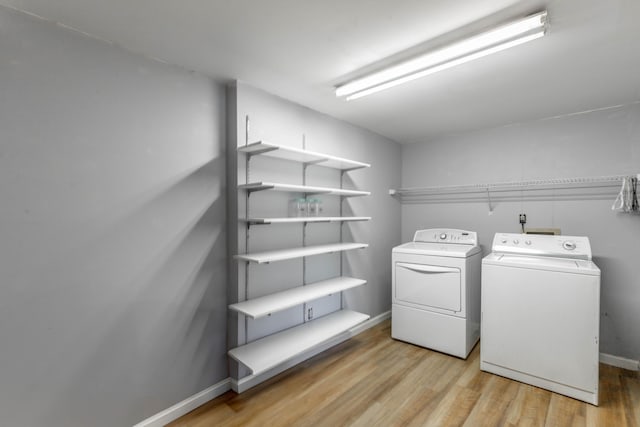 clothes washing area with light wood-style flooring, laundry area, washer and clothes dryer, and baseboards