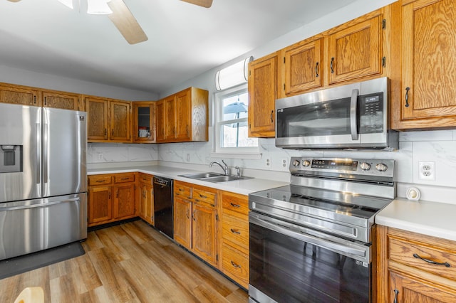 kitchen with stainless steel appliances, light countertops, brown cabinets, and a sink