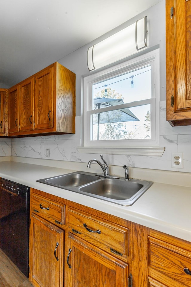 kitchen with a sink, brown cabinetry, light countertops, and dishwasher