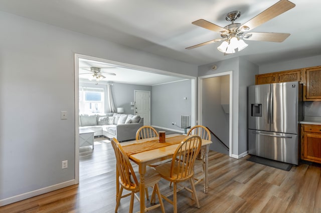 dining space featuring light wood-type flooring, baseboards, and a ceiling fan