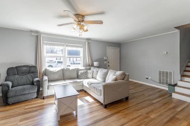 living room featuring ornamental molding, visible vents, stairway, and light wood finished floors