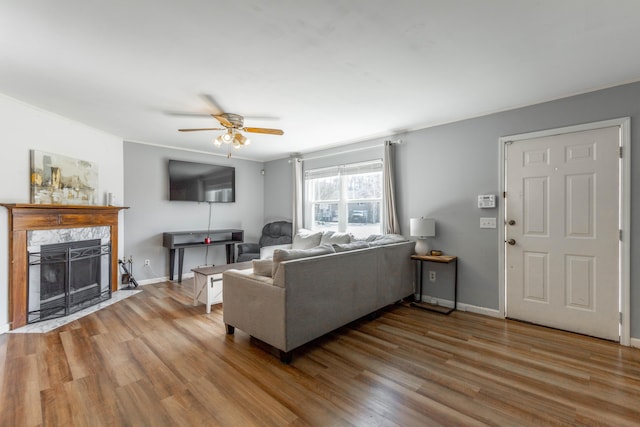 living area with ceiling fan, baseboards, wood finished floors, and a tile fireplace