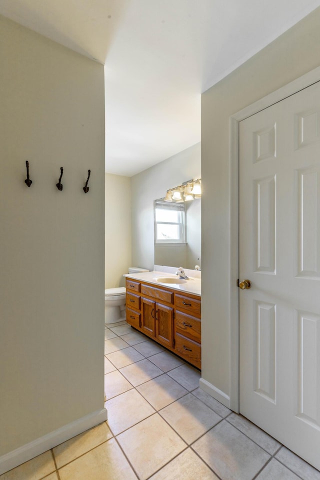 bathroom featuring toilet, tile patterned flooring, baseboards, and vanity