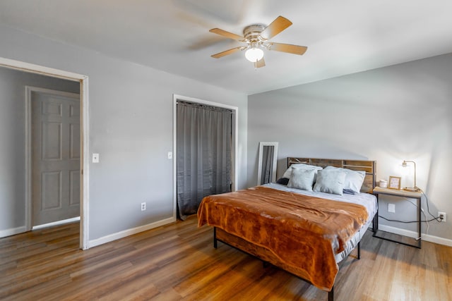 bedroom with a closet, ceiling fan, baseboards, and wood finished floors