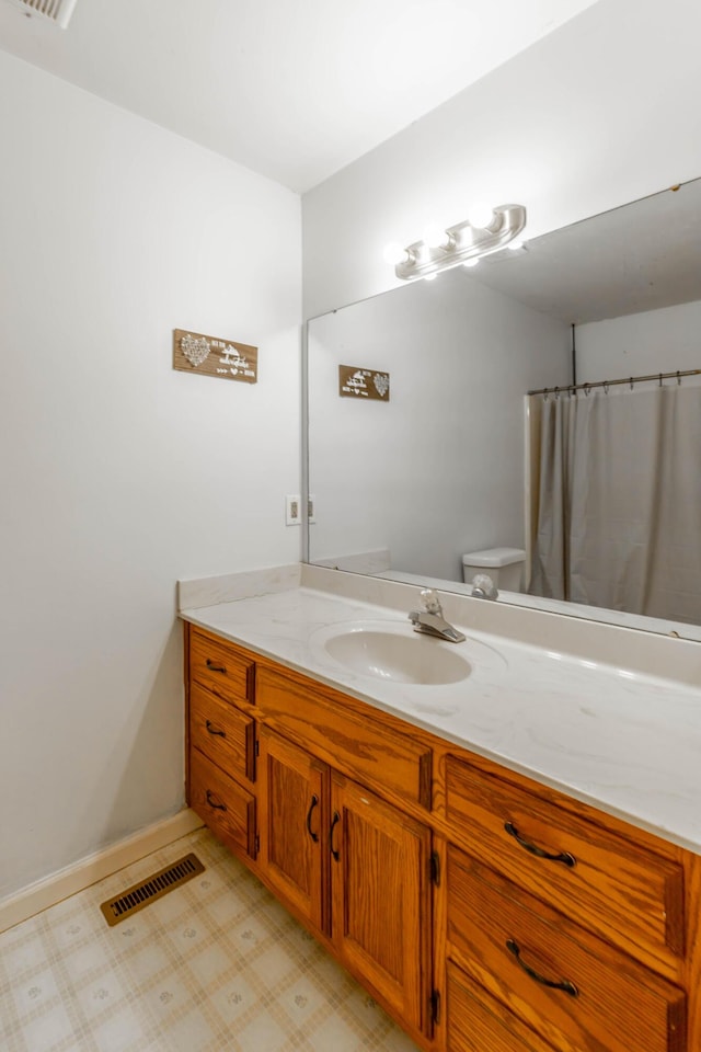 full bath featuring toilet, vanity, visible vents, baseboards, and tile patterned floors