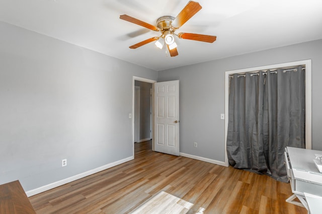 unfurnished bedroom with ceiling fan, baseboards, and wood finished floors