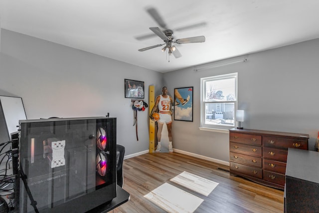 interior space featuring ceiling fan, baseboards, and wood finished floors