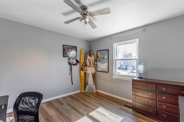 office featuring a ceiling fan, visible vents, baseboards, and wood finished floors