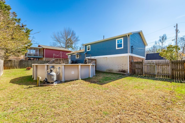 back of house with a fenced backyard, a fenced in pool, and a lawn