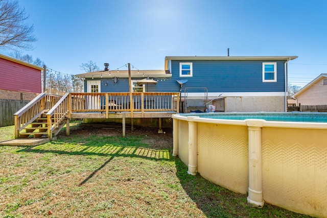 rear view of property with a deck, fence, stairs, a yard, and an outdoor pool