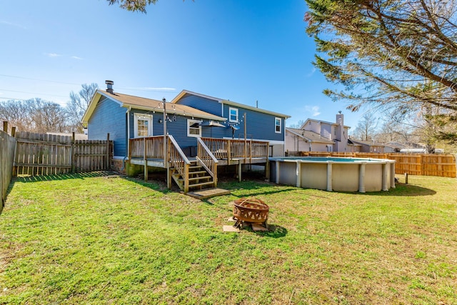 rear view of house featuring a fire pit, a fenced in pool, a fenced backyard, a deck, and a yard