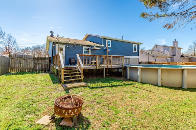 rear view of house with a deck, a lawn, a fenced backyard, and a fenced in pool